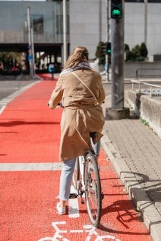 traffic, city transport and people concept - woman cycling along red bike lane with signs of bicycle on street in tallinn, estonia. woman cycling along red bike lane road in city