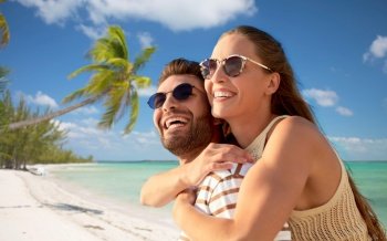 travel, tourism and people concept - happy couple in sunglasses over tropical beach background in french polynesia. happy couple in sunglasses on exotic beach