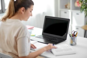 education, online school and distant learning concept - female student woman with laptop computer, notebook and book at home. student woman with laptop, notebook and book
