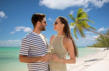 travel, tourism and people concept - happy couple in sunglasses drinking champagne over tropical beach background in french polynesia. happy couple drinking champagne on exotic beach