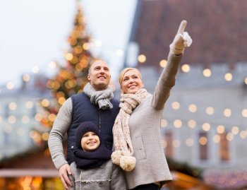 winter holidays, leisure and people concept - happy family over christmas market background. happy family at christmas market or amusement park
