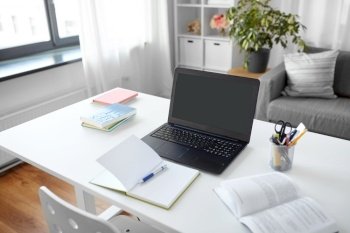 interior, education and business concept - open laptop computer, notebook and book on table at home office. laptop, notebook and book on table at home office