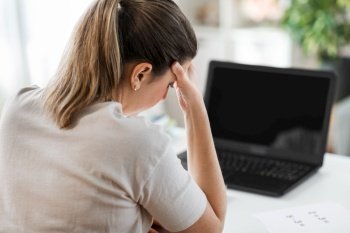 distant education, remote job and health concept - tired female teacher with laptop computer having headache at home office. tired teacher with laptop having headache at home