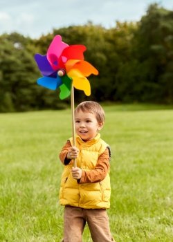 childhood, leisure and people concept - happy little boy with pinwheel playing at park. happy little boy with pinwheel playing at park