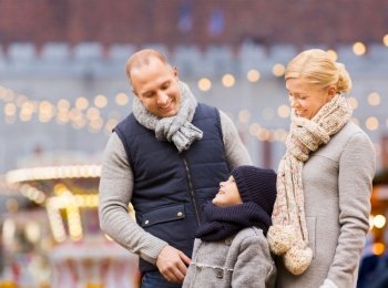 winter holidays, leisure and people concept - happy family talking over christmas market or amusement park background. happy family at christmas market or amusement park