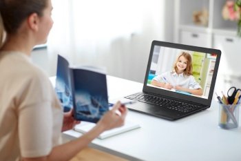 education, school and distant learning concept - female math teacher laptop computer and book having online class with student girl at home. math teacher having online class with student girl