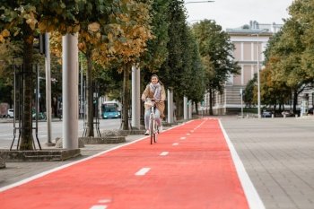 traffic, city transport and people concept - happy smiling woman riding bicycle along red bike lane or two way road on street. woman riding bicycle along red bike lane in city