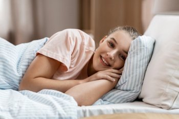 people, bedtime and sleeping concept - happy smiling awake girl lying in bed at home. happy smiling awake girl lying in bed at home