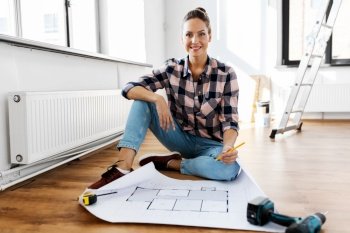 repair, people and real estate concept - woman with blueprint and pencil sitting on floor at home. woman with blueprint sitting on floor at home