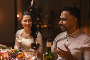 holidays, party and celebration concept - happy man with friends having christmas dinner at home and drinking wine. happy friends drinking wine at christmas party