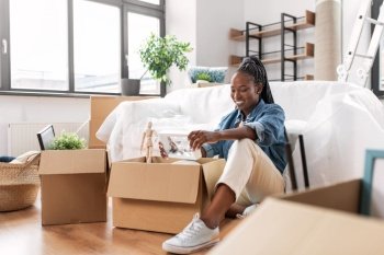 moving, people and real estate concept - happy smiling woman with hourglass unpacking boxes at new home. happy woman unpacking boxes and moving to new home