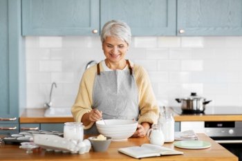 people and culinary concept - happy smiling woman cooking food on kitchen at home. happy woman cooking food on kitchen at home