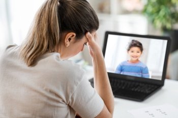distant education, remote job and health concept - tired female teacher with little student girl laptop computer having headache at home office. tired teacher with laptop having headache at home
