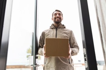 shipping, transportation and people concept - happy smiling delivery man with parcel box at open door. smiling delivery man with parcel box at open door