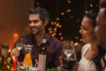 holidays and celebration concept - happy man having christmas dinner with friends and drinking wine at home. happy friends drinking wine at christmas dinner