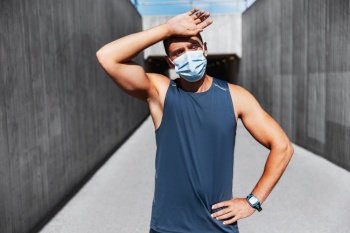 fitness, sport and health concept - tired young man in medical mask doing sports outdoors. tired man in medical mask doing sports outdoors
