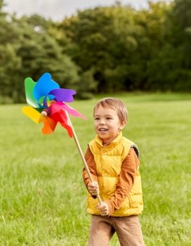 childhood, leisure and people concept - happy little boy with pinwheel playing at park. happy little boy with pinwheel playing at park