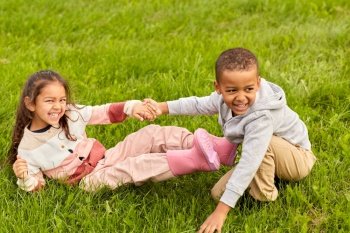 childhood, leisure and people concept - happy smiling little boy and girl having fun at park. happy little boy and girl having fun at park