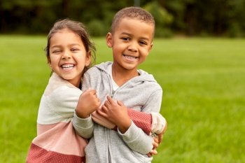 childhood, leisure and people concept - happy smiling little boy and girl hugging at park. happy little boy and girl hugging at park