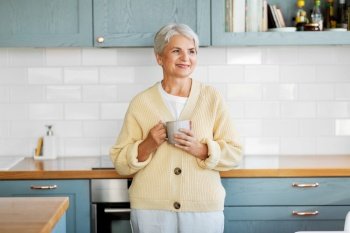 leisure and people concept - happy smiling woman with cup of coffee on kitchen at home. happy woman with cup of coffee on kitchen at home