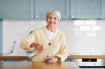 leisure and people concept - happy smiling woman pouring water from jug to drinking glass on kitchen at home. happy woman with jug of water on kitchen at home