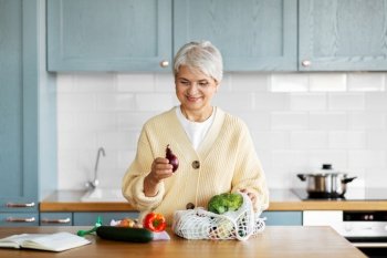 healthy eating, food cooking and culinary concept - happy smiling woman with vegetables and cook book on kitchen. woman with vegetables and cook book on kitchen