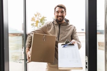 shipping, transportation and people concept - happy smiling delivery man with parcel box and clipboard at open door. smiling delivery man with parcel box at open door