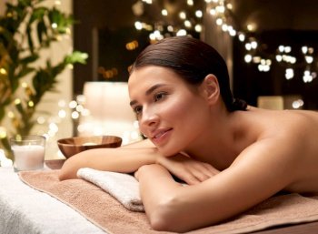 wellness, beauty and relaxation concept - young woman lying at spa or massage parlor over christmas lights on window background. young woman lying at spa or massage parlor
