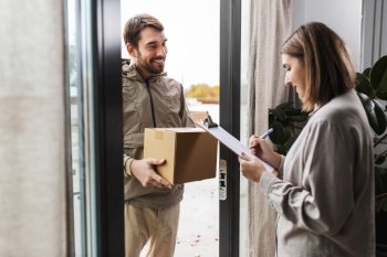 shipping, transportation and people concept - delivery man with parcel box and customer signing papers on clipboard at home. delivery man with parcel box and customer at home