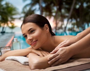 wellness, beauty and relaxation concept - beautiful young woman lying and having massage at spa over tropical beach background in french polynesia. woman lying and having massage at spa