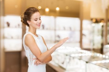 luxury and people concept - smiling woman in white dress wearing diamond ring over jewelry store background. smiling woman with diamond ring at jewelry store