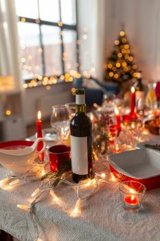 serving, winter holidays and celebration concept - bottle of red wine on table served for christmas dinner party at home. bottle of wine on table served for christmas party