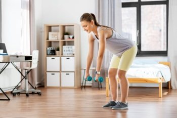 fitness, sport and healthy lifestyle concept - happy teenage girl with dumbbells exercising at home. teenage girl with dumbbells exercising at home