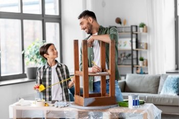 family, diy and home improvement concept - happy smiling father and son with ruler measuring old round wooden table for renovation at home. father and son with ruler measuring old table