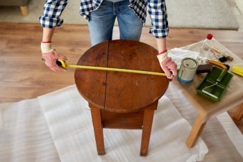 repair, diy and home improvement concept - close up of woman with ruler measuring old round wooden table for renovation. woman with ruler measuring table for renovation