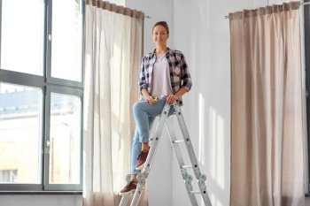 home improvement, decoration and renovation concept - happy smiling woman on ladder with ruler hanging curtains. woman on ladder hanging curtains at home