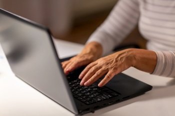 technology and people concept - close up of senior woman hands typing on laptop at home. hands of senior woman typing on laptop at home