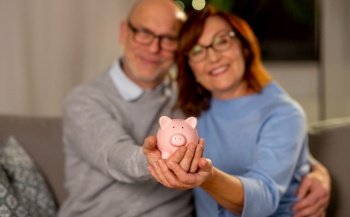 finance, savings and people concept - close up of happy senior couple with piggy bank at home. happy senior couple with piggy bank at home