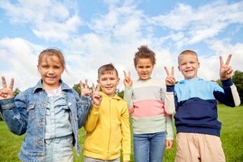 childhood, leisure and people concept - group of happy kids showing peace sign at park. happy children showing peace sign at park