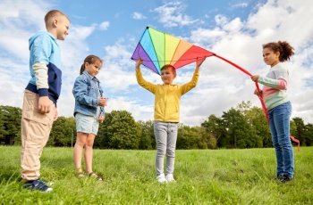 childhood, leisure and people concept - group of happy kids with kite playing at park. happy kids with kite playing at park
