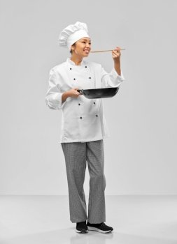 food cooking, culinary and people concept - happy smiling female chef with frying pan and spoon over grey background. smiling female chef with frying pan
