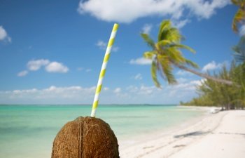 summer holidays, travel and tourism concept - close up of coconut drink with paper straw over tropical beach background in french polynesia. coconut drink with paper straw over tropical beach
