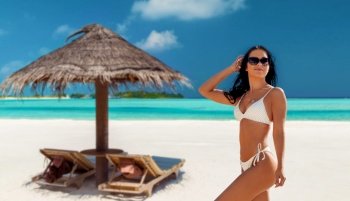 people, summer and swimwear concept - happy smiling young woman in bikini swimsuit over tropical beach background in french polynesia. smiling young woman in bikini swimsuit on beach