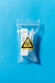medicine, self testing and pandemic concept - used coronavirus nasal test kit in recycling bag on blue background. used coronavirus self testing kit in recycling bag