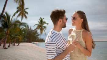 leisure, travel and tourism concept - happy couple in sunglasses drinking champagne over tropical beach background in french polynesia. happy couple drinking champagne on summer beach