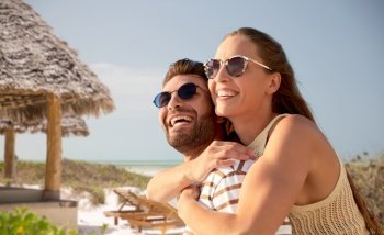 travel, tourism and people concept - happy couple in sunglasses hugging over tropical beach background in french polynesia. happy couple in sunglasses hugging on summer beach