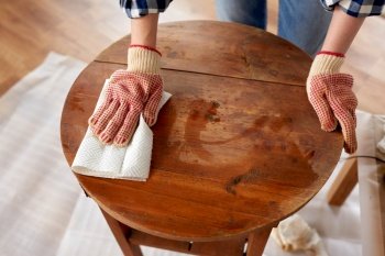 furniture renovation, diy and home improvement concept - close up of woman cleaning or degreasing old round wooden table surface with paper tissue. woman cleaning old table surface with paper tissue