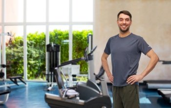 fitness, sport and healthy lifestyle concept - smiling man in sports clothes over gym background. smiling man in sports clothes in gym