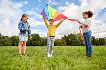 childhood, leisure and people concept - group of happy kids with kite playing at park. happy kids with kite playing at park