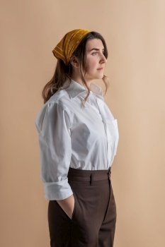 people, style and fashion concept - portrait of beautiful woman in white male shirt and trousers with bandana on her head over beige background. portrait of beautiful woman over beige background